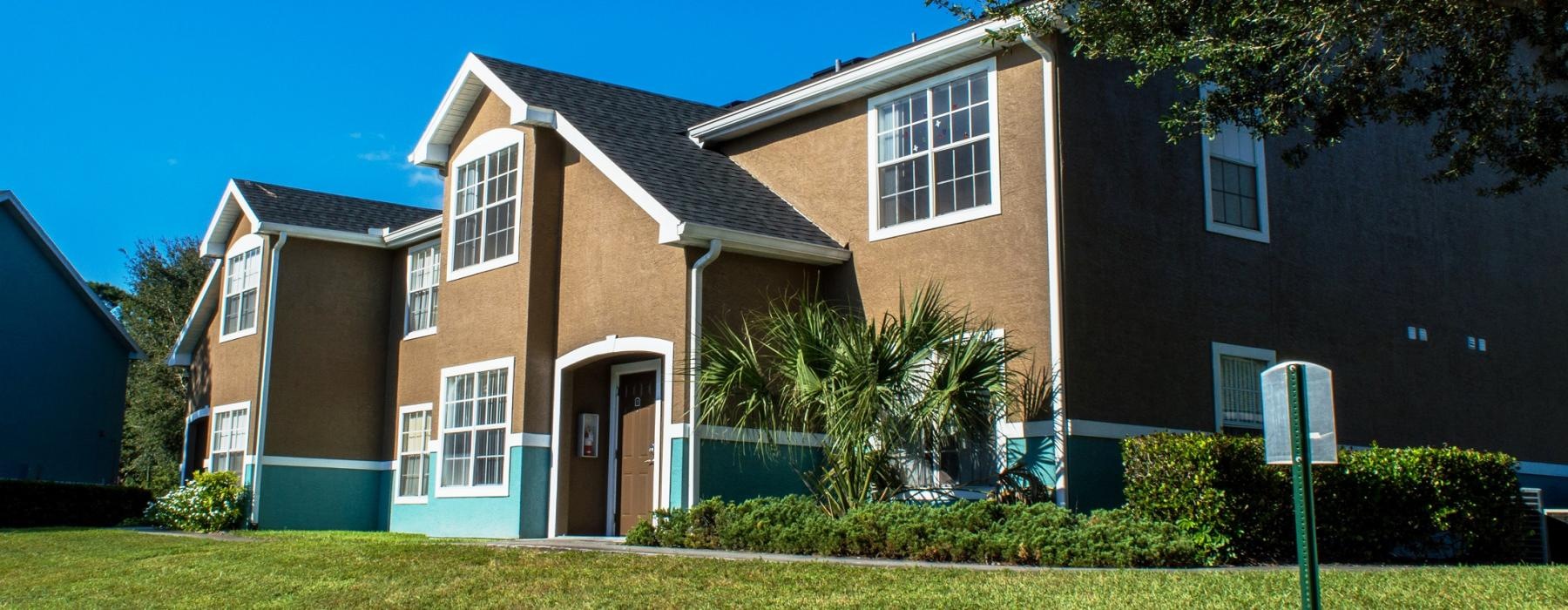 apartment exterior with lots of grass and trees